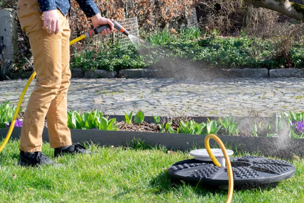 Arrosage du jardin avec de l’eau gratuite issue d’une citerne eau de pluie enterrée, grâce à une pompe et un tuyau connecté.